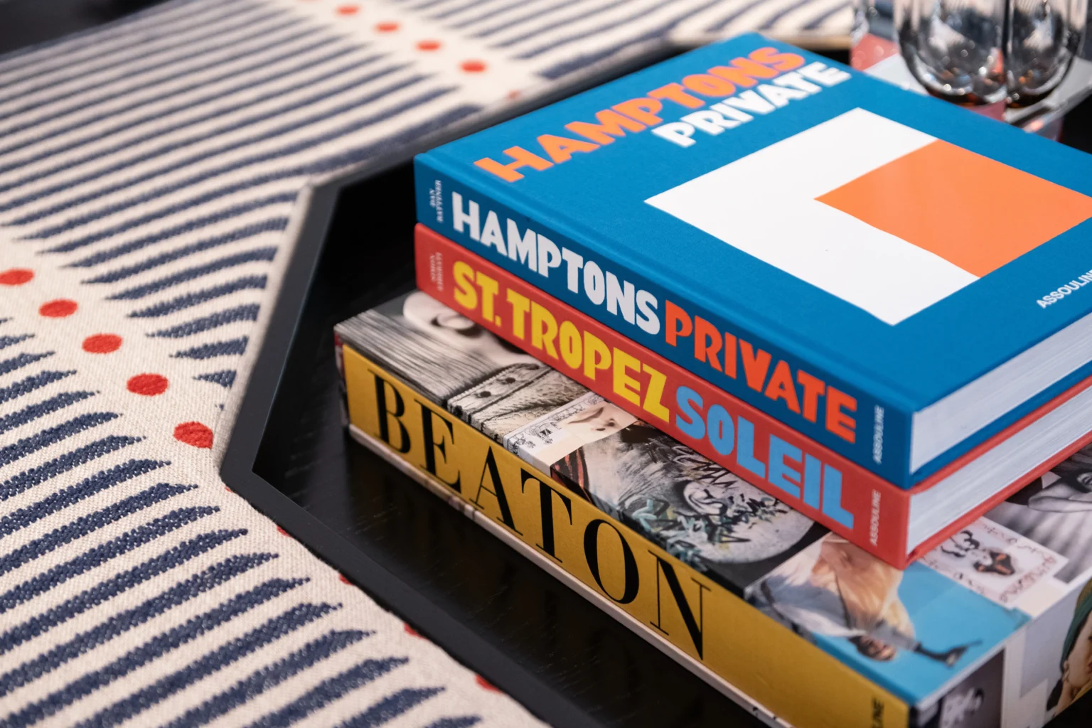 A stack of design books styled on a striped rug in a Tobias Oliver study