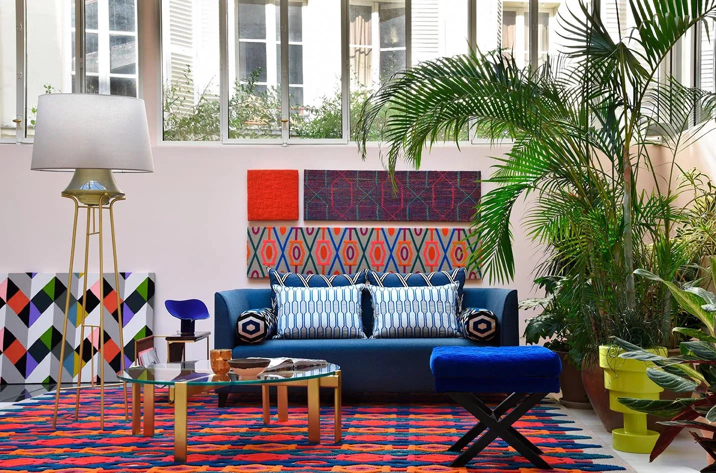 Boussac geometric fabrics and cushions in a colourful sitting room with a blue sofa