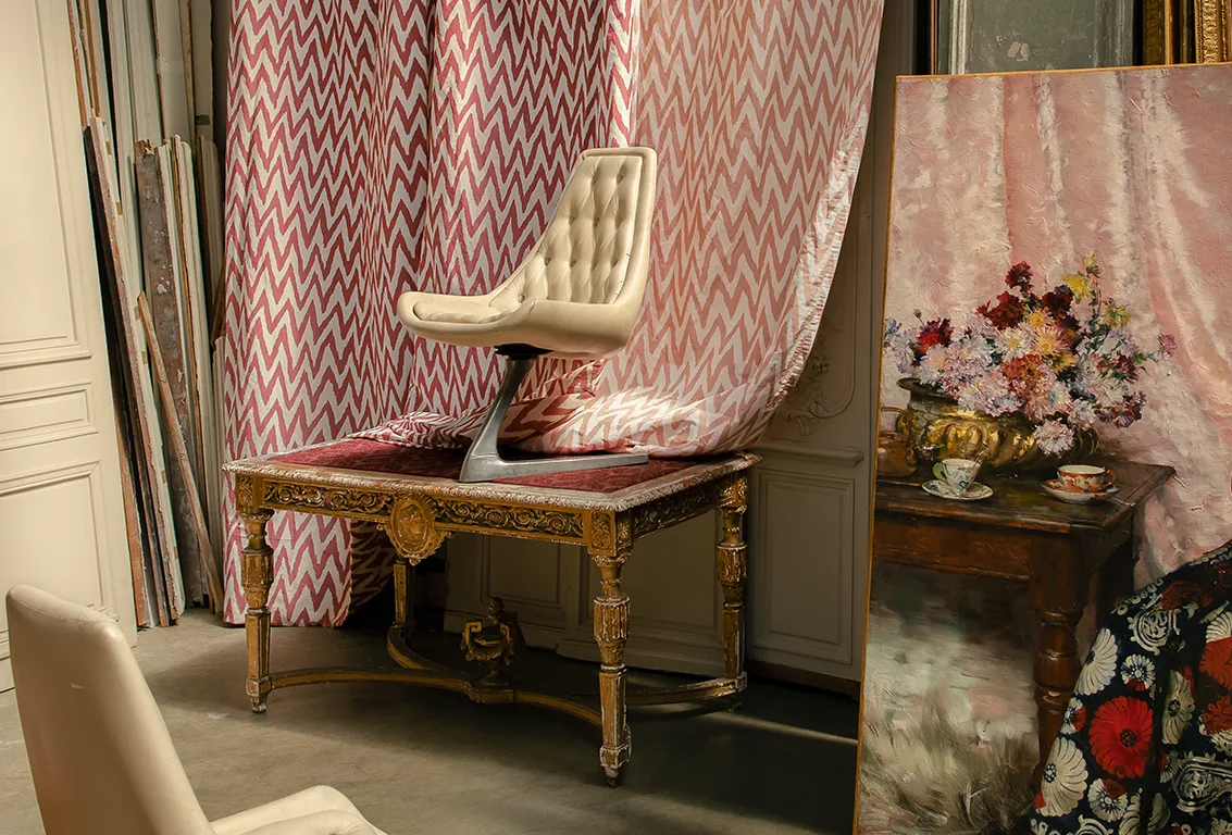 Le Manach pink and ivory patterned fabric beside a gilded bench and a floral painting